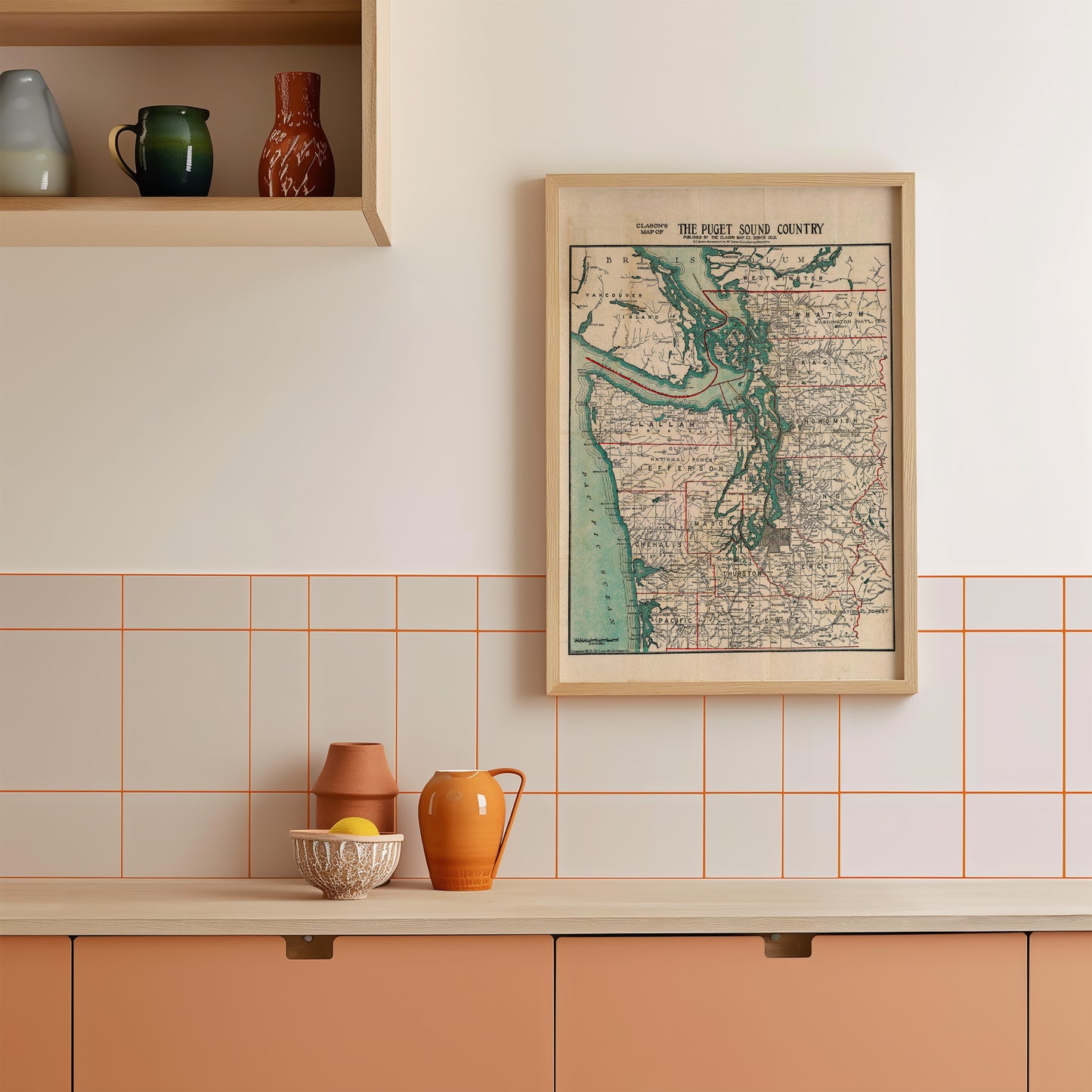 a kitchen counter with various items on it, including a framed map, a bowl, a pitcher, and a vase.