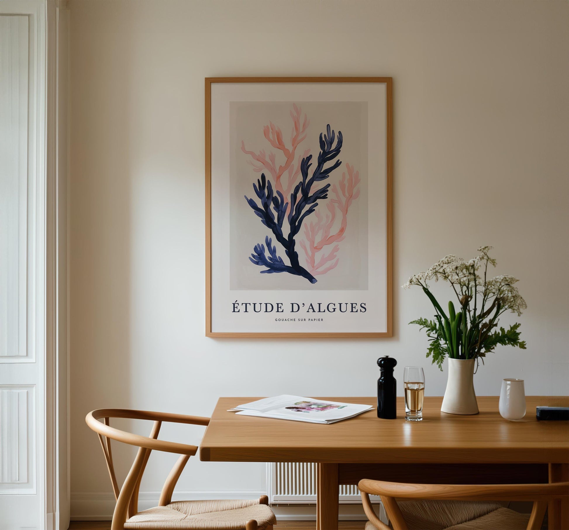 a dining room with a wooden table, two chairs, a framed poster of a plant, and a vase of flowers.