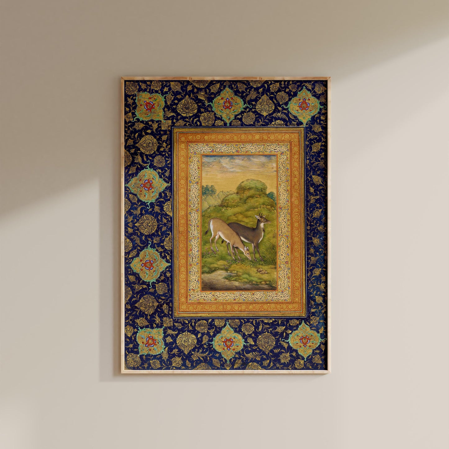 a framed painting of a deer in a grassy field, with a decorative border and floral patterns surrounding the artwork.