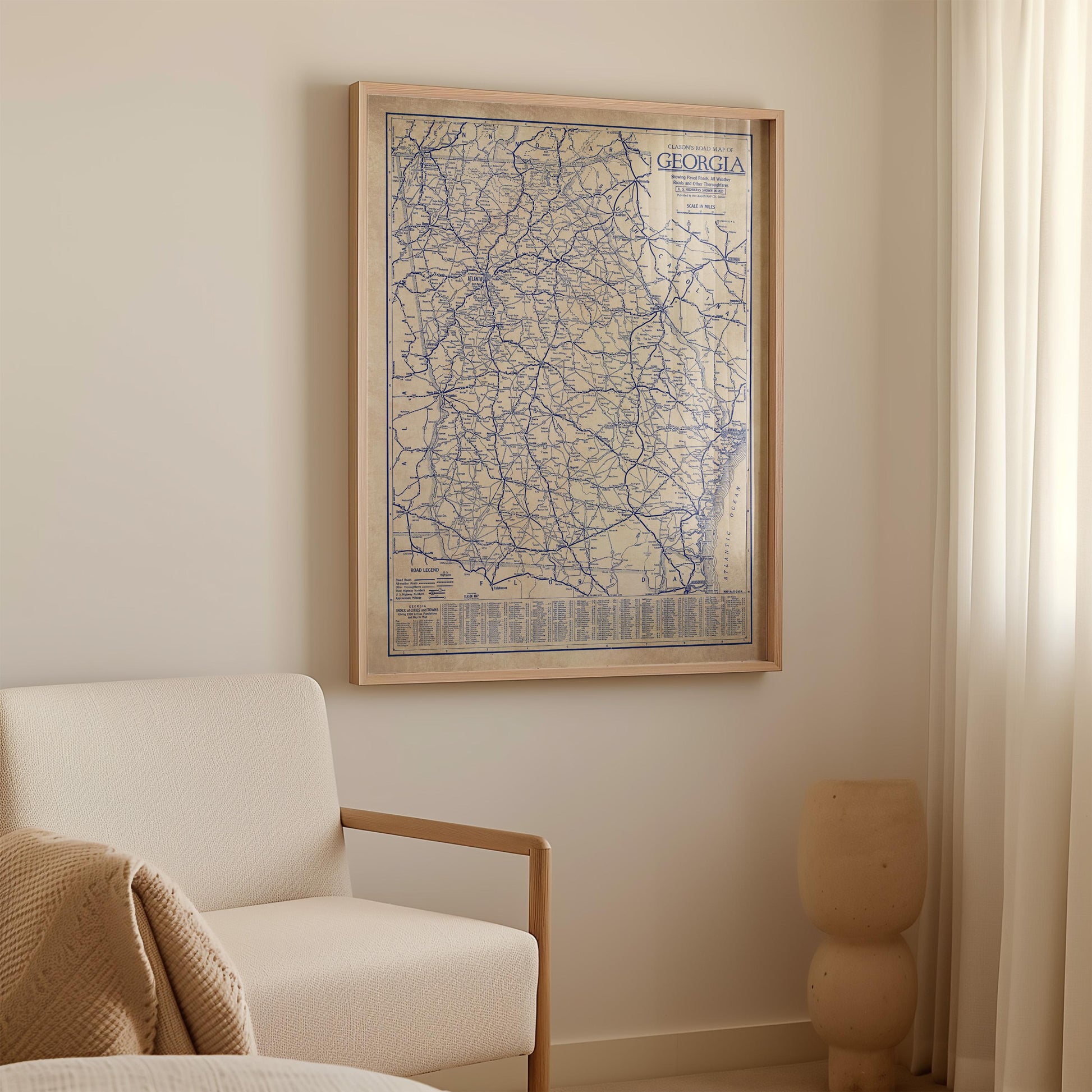 a framed map of Georgia hanging on a wall, with a white sofa and a small decorative object in the foreground.
