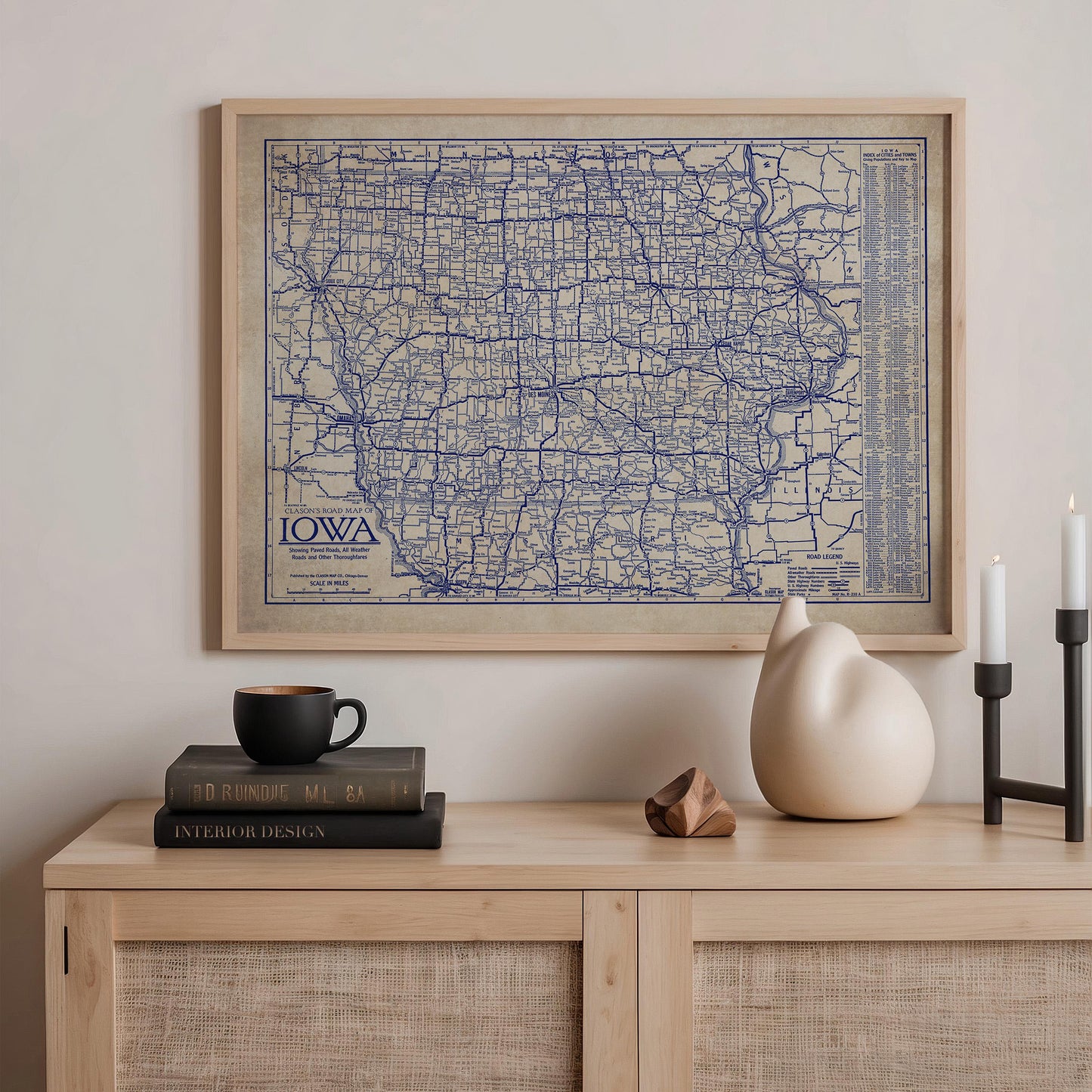 a framed map of Iowa, a wooden shelf with a stack of books, a ceramic vase, and a small sculpture.