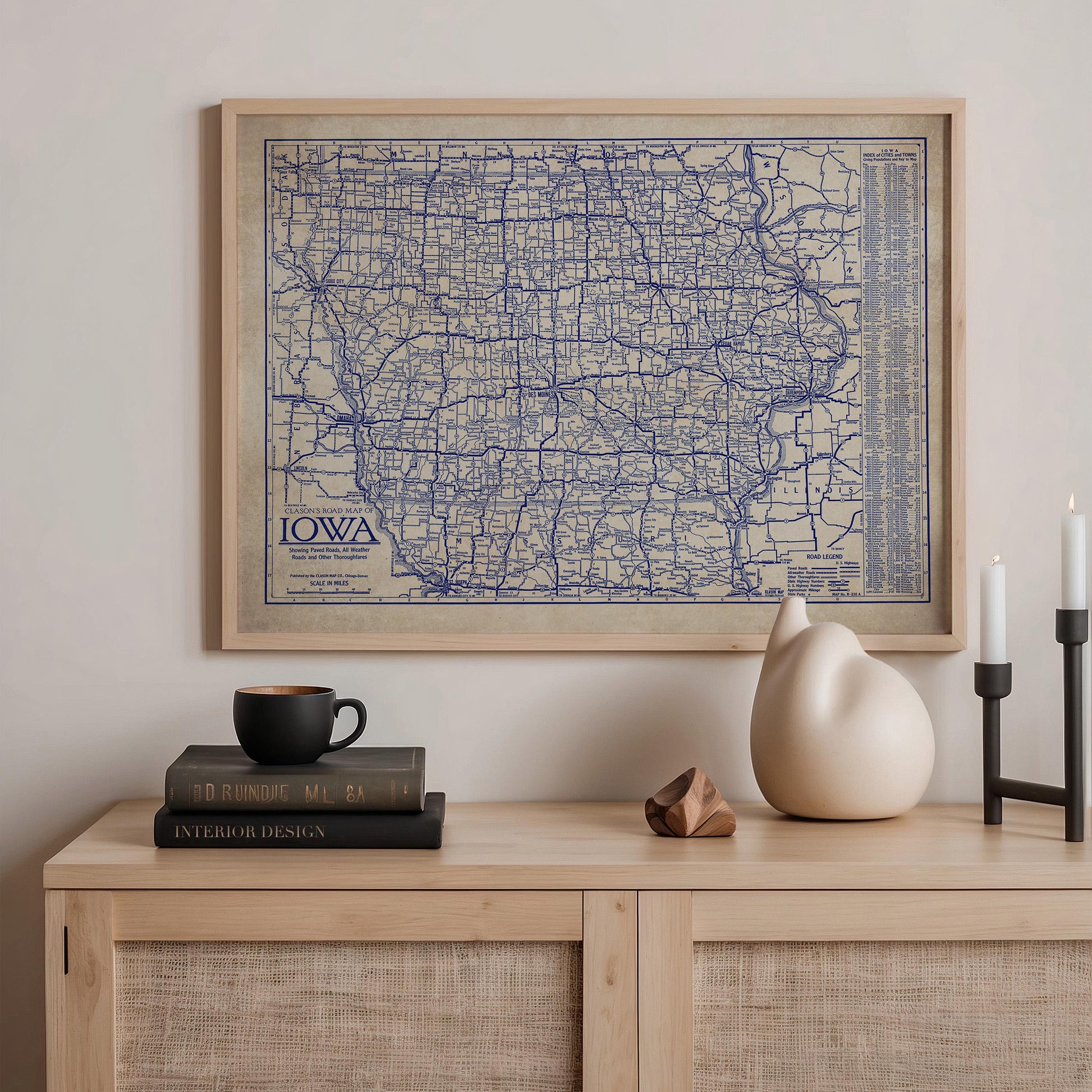 a framed map of Iowa, a wooden shelf with a stack of books, a ceramic vase, and a small sculpture.