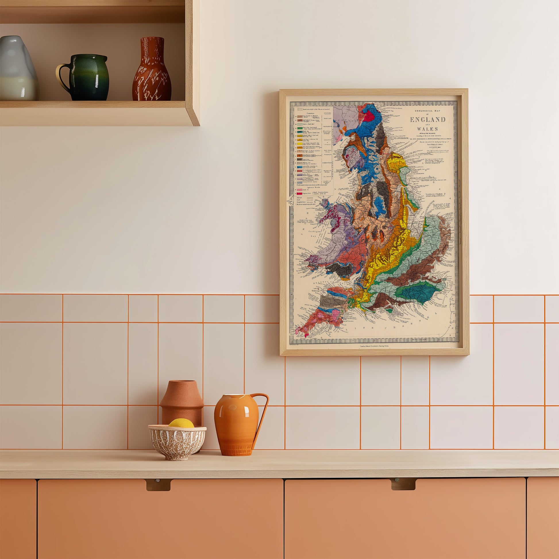 a kitchen counter with various items on it, including a framed map of England and Wales, a bowl, a pitcher, and a vase.