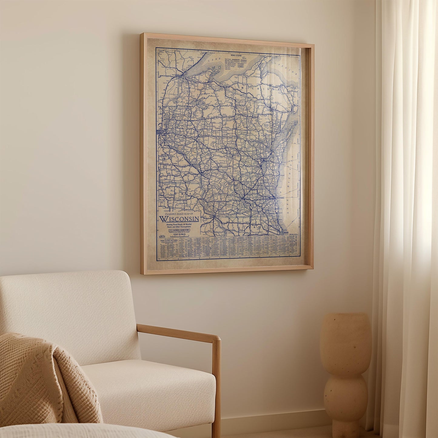 a framed map of Wisconsin hanging on a wall in a room with a white sofa and a small vase.