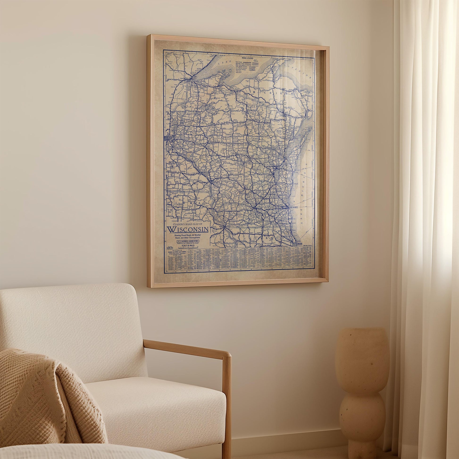 a framed map of Wisconsin hanging on a wall in a room with a white sofa and a small vase.