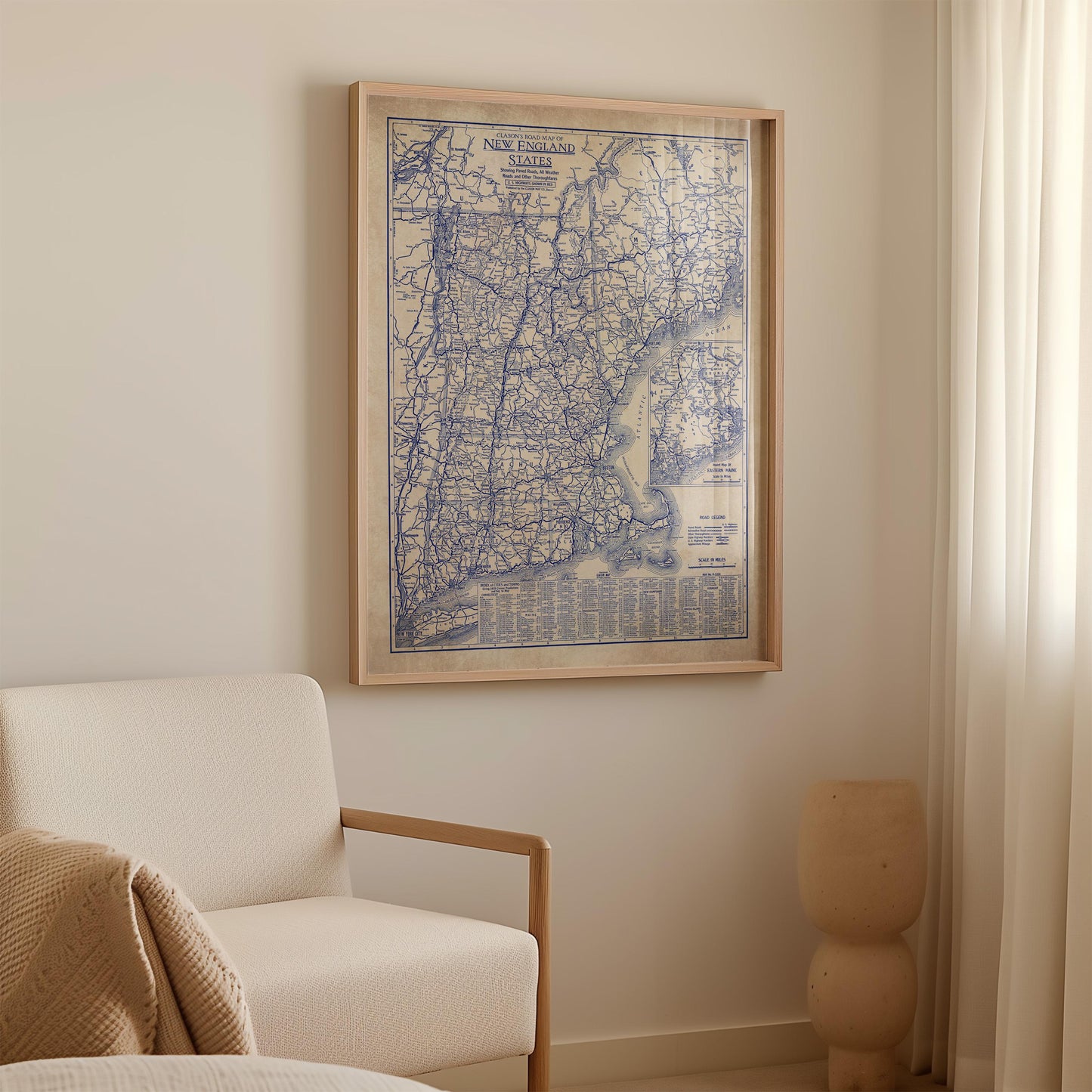 a framed map of New England hanging on a wall in a room with a white sofa and a small sculpture.
