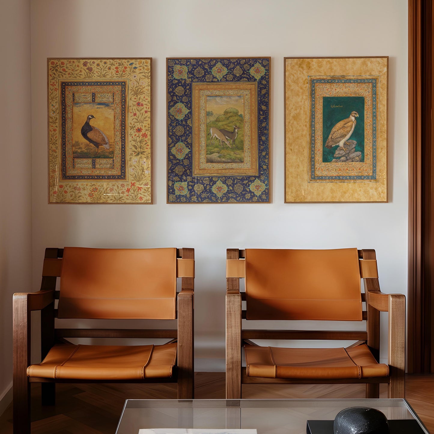 three ornate paintings of birds, each with a different color and frame design, hanging on a wall above two brown leather chairs.