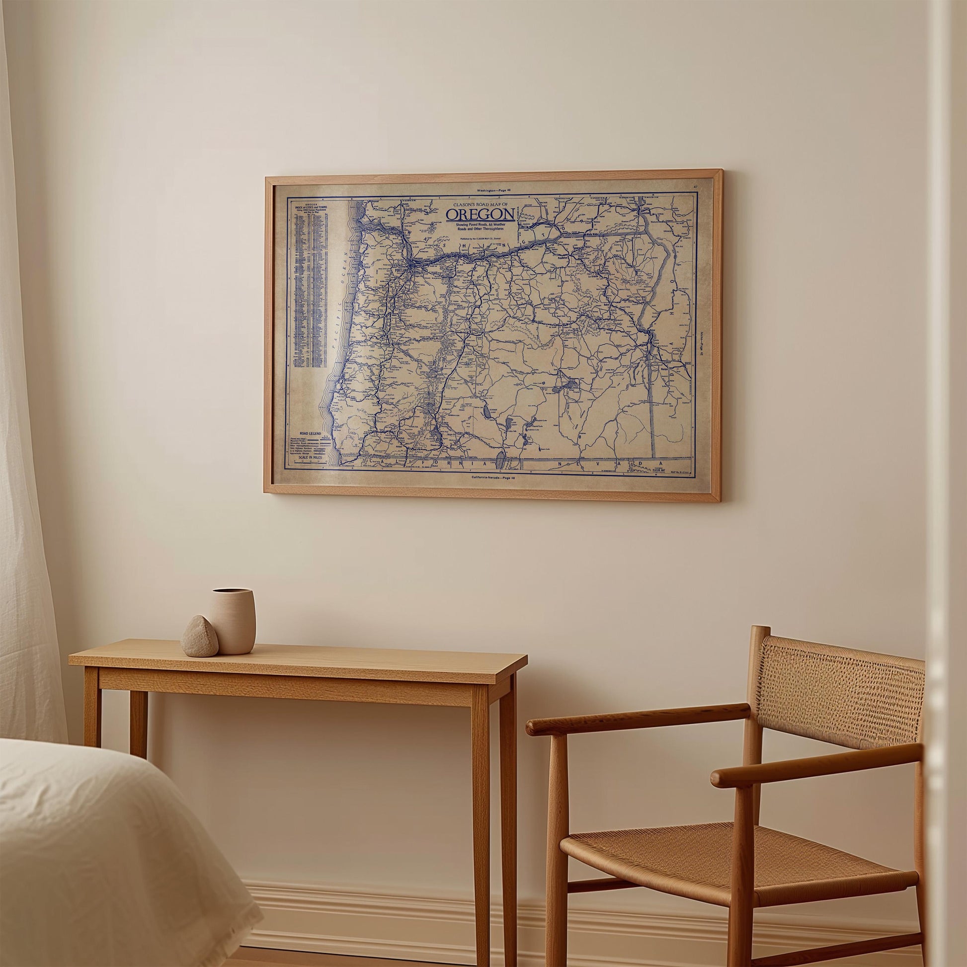 a wooden table with a small vase on it, and a wooden chair next to it. Above the table, there is a framed map of Oregon hanging on the wall.