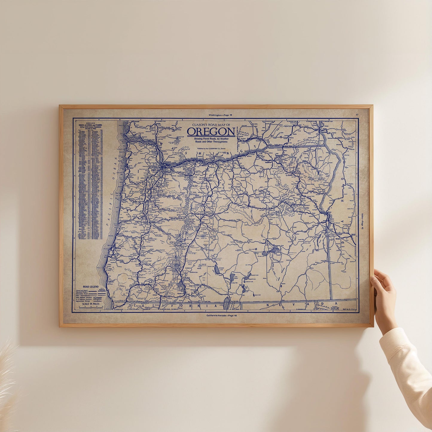 A framed map of Oregon is being held up against a white wall.