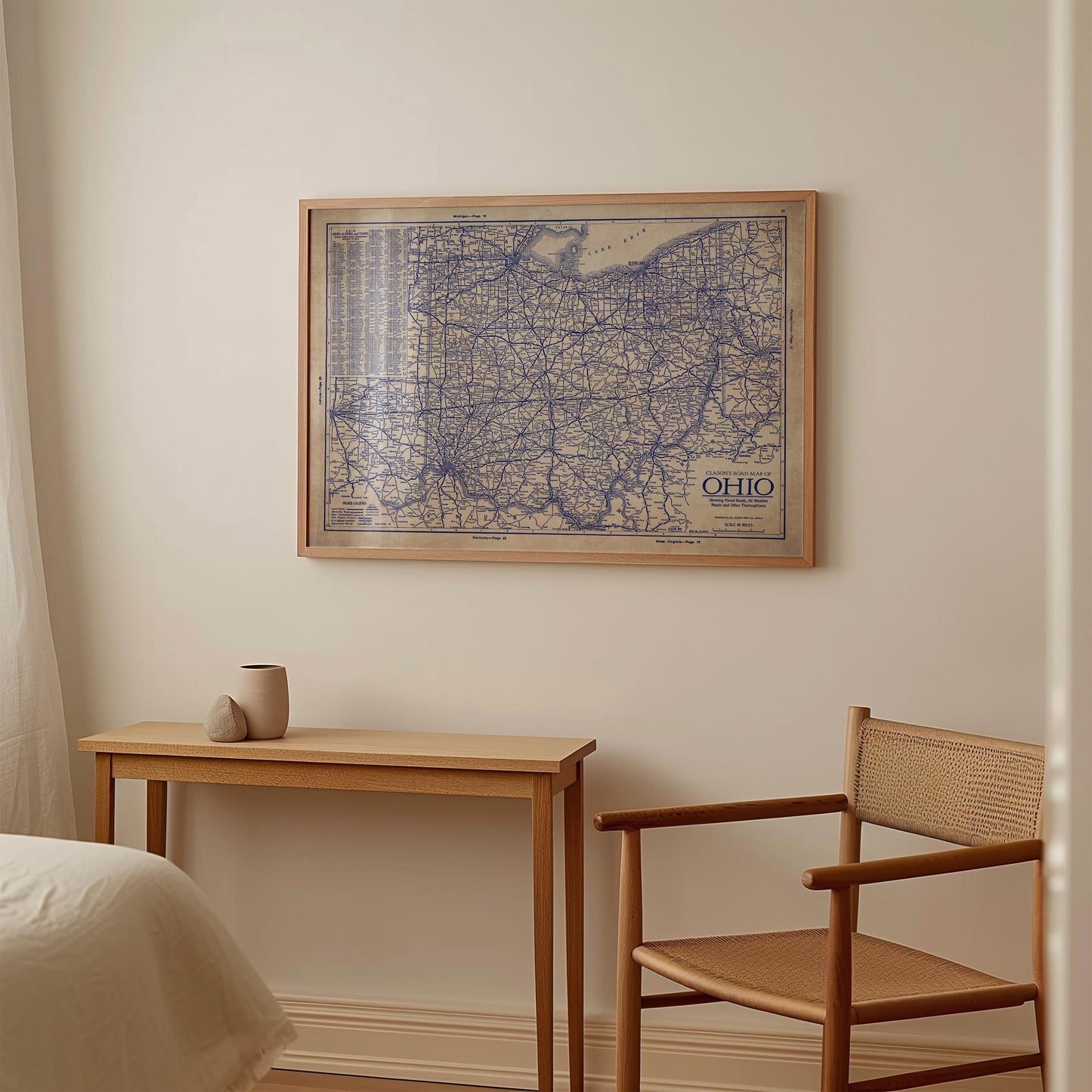 a wooden table with a small vase on it, and a wooden chair is positioned next to the table. Above the table, there is a framed map of Ohio hanging on the wall.