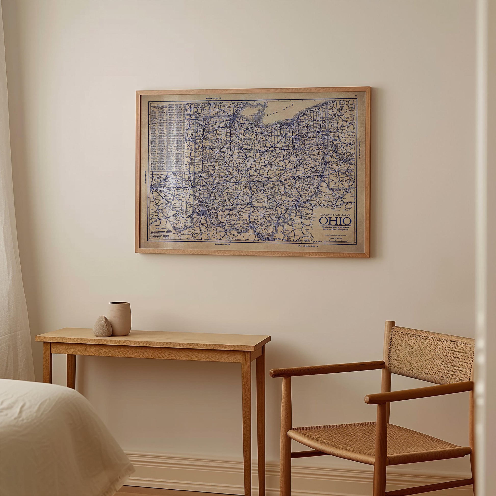 a wooden table with a small vase on it, and a wooden chair is positioned next to the table. Above the table, there is a framed map of Ohio hanging on the wall.