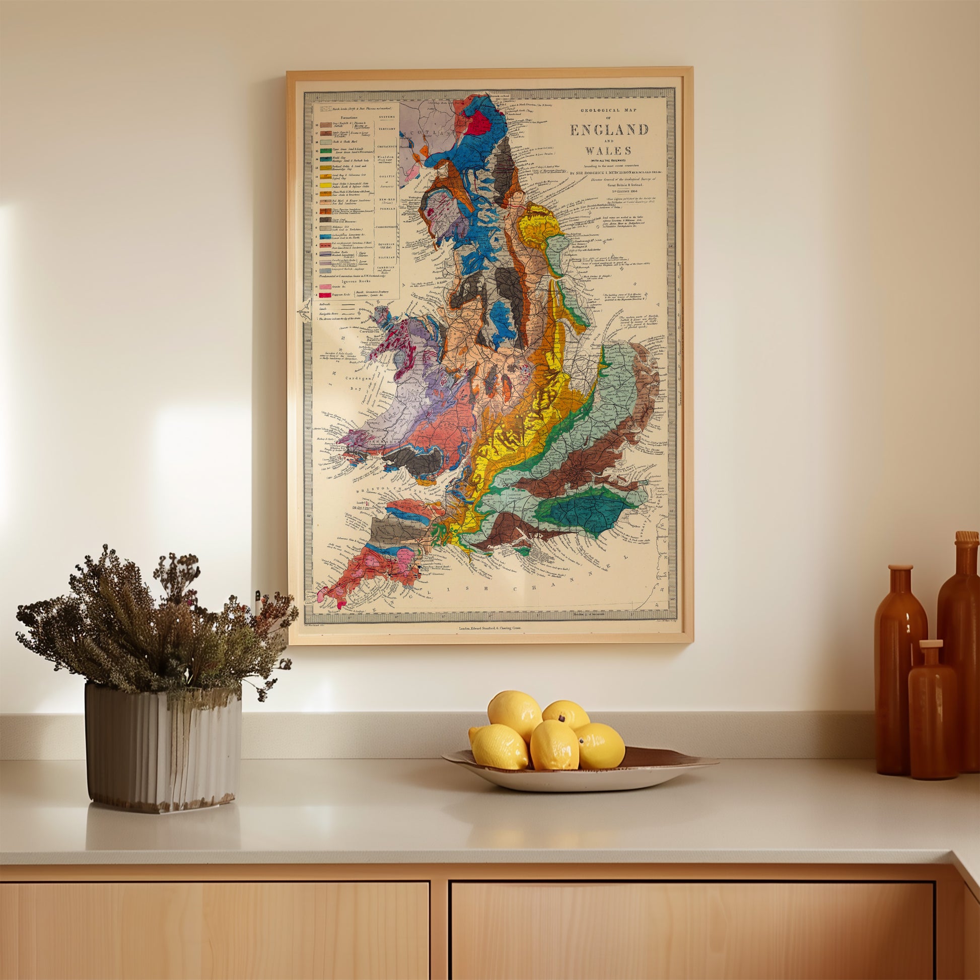 a kitchen counter with a framed map of England and Wales hanging above it, a bowl of fruit, and some decorative items on the counter.