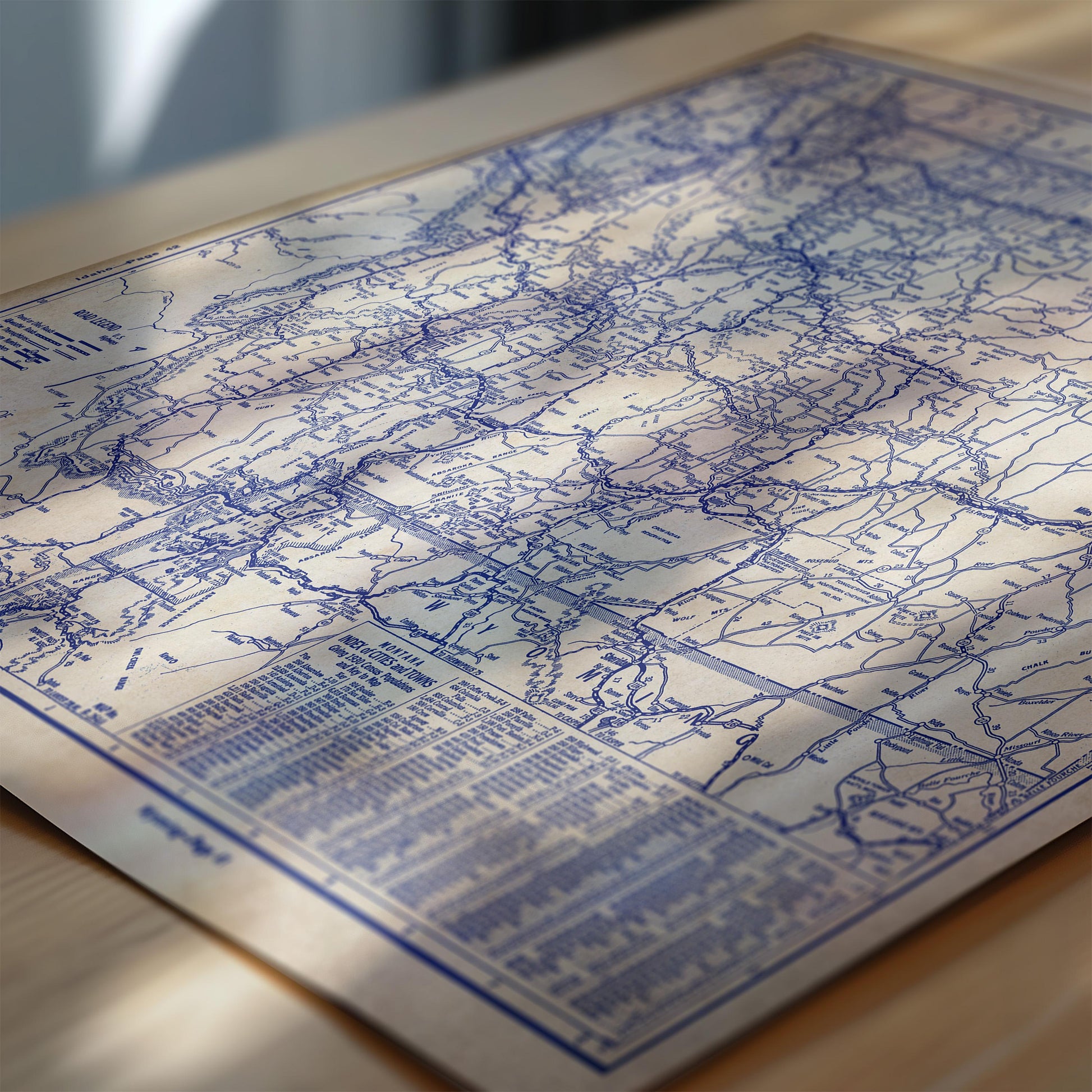 The image is a detailed map of a region, with various roads and landmarks marked on it. The map appears to be in blue and white colors, and it is placed on a wooden surface.