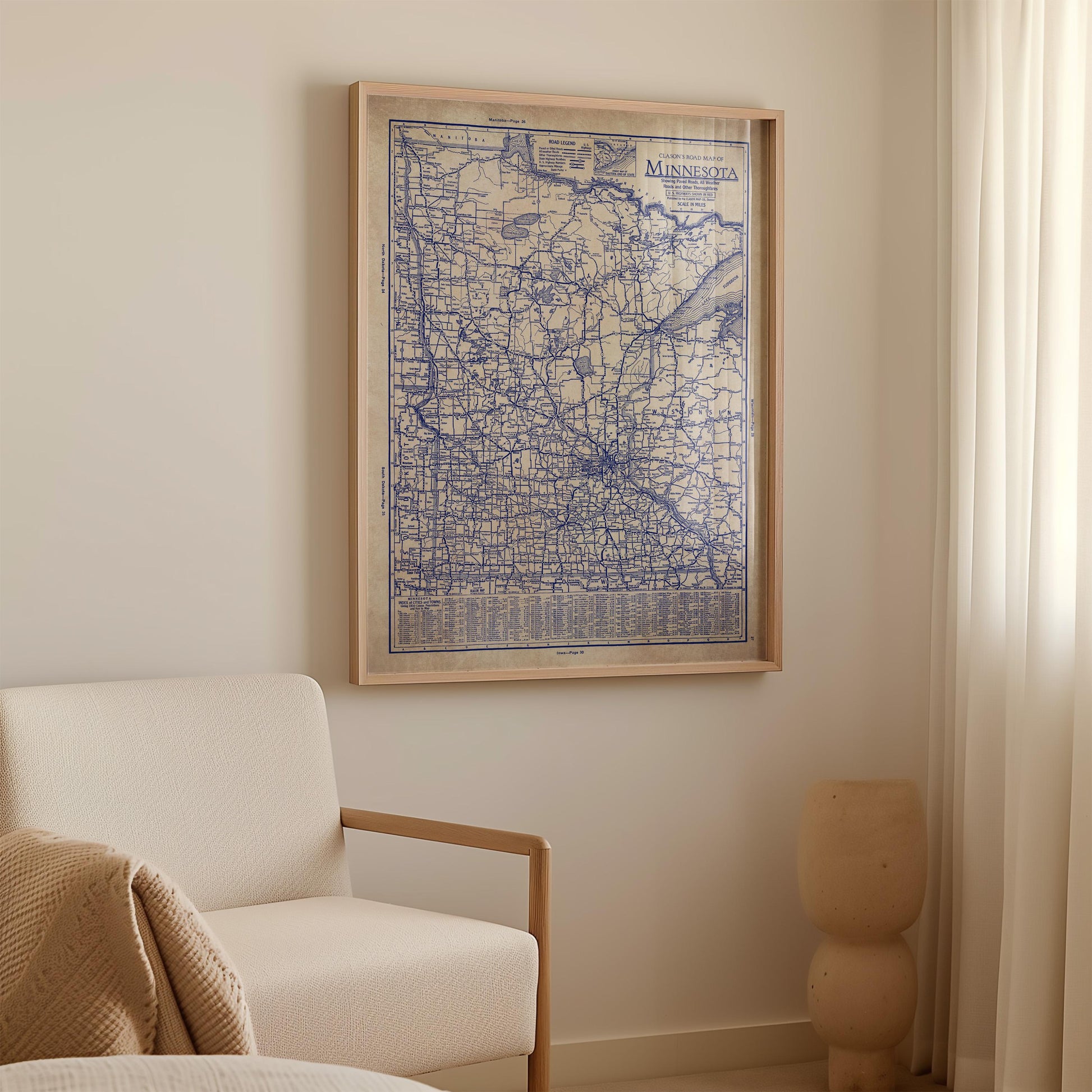 a framed map of Minnesota hanging on a wall in a room with a white sofa and a small vase.