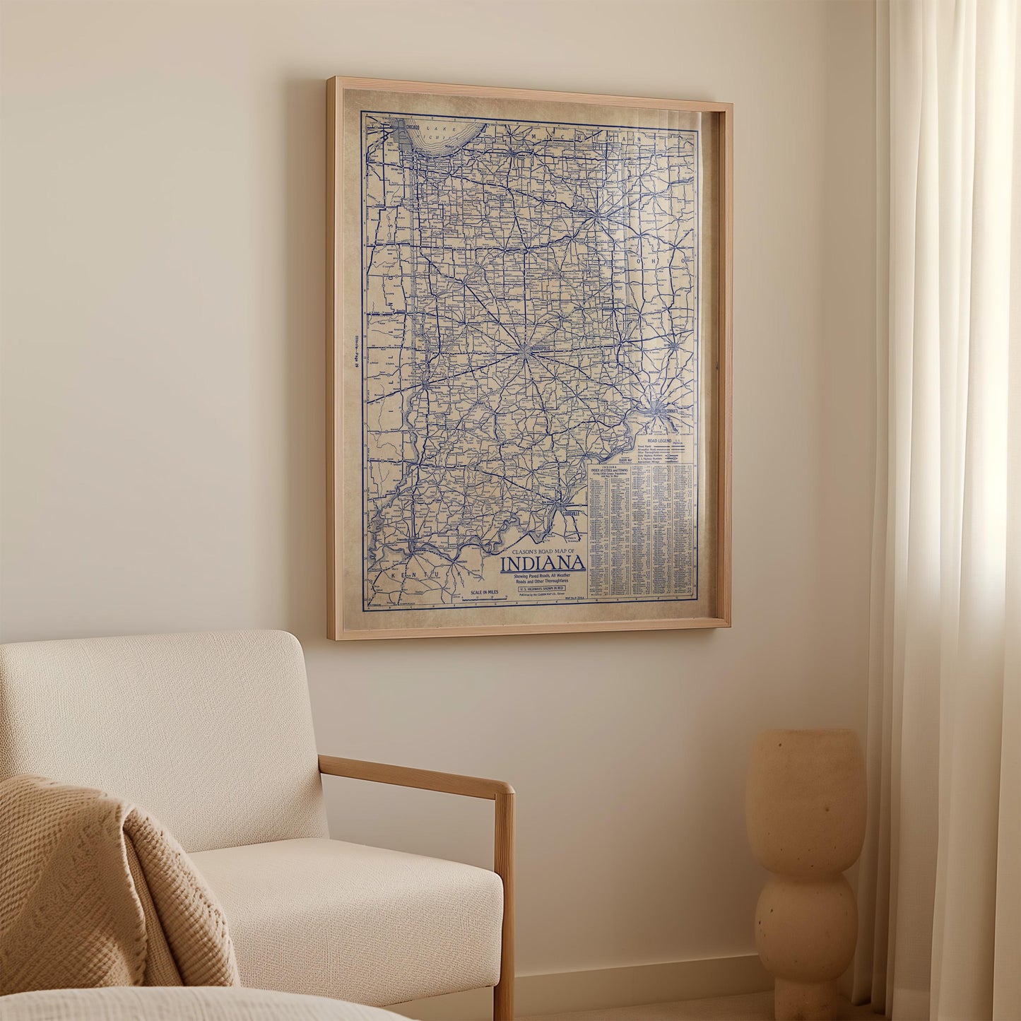 a framed map of Indiana hanging on a wall, with a white sofa and a small decorative object in the foreground.