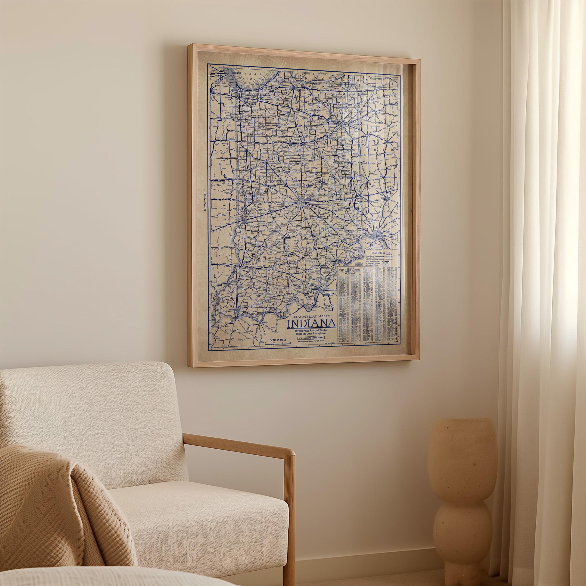 a framed map of Indiana hanging on a wall, with a white sofa and a small decorative object in the foreground.
