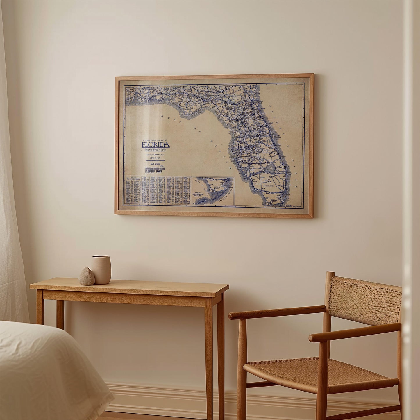 a framed map of Florida hanging on a wall, with a small table and a chair positioned below it.