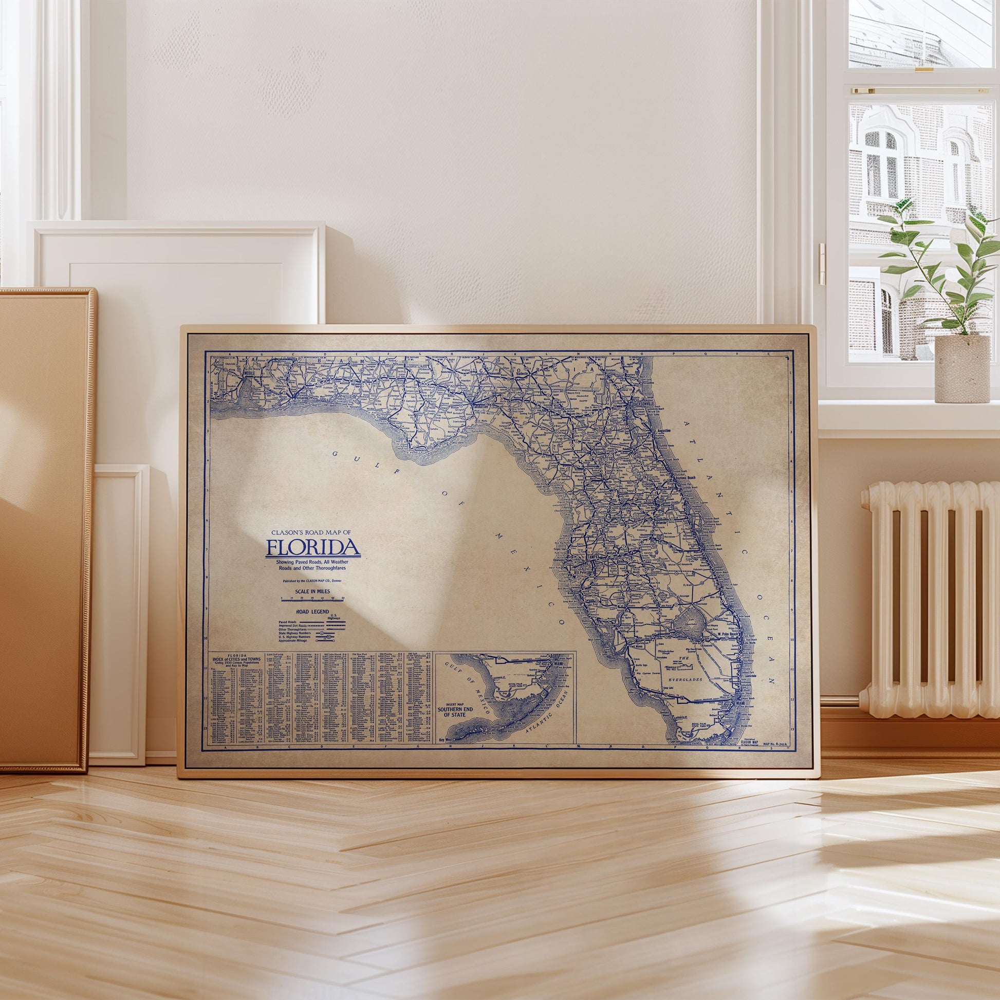 A framed map of Florida is displayed on a wooden floor in a room with a window and a radiator.