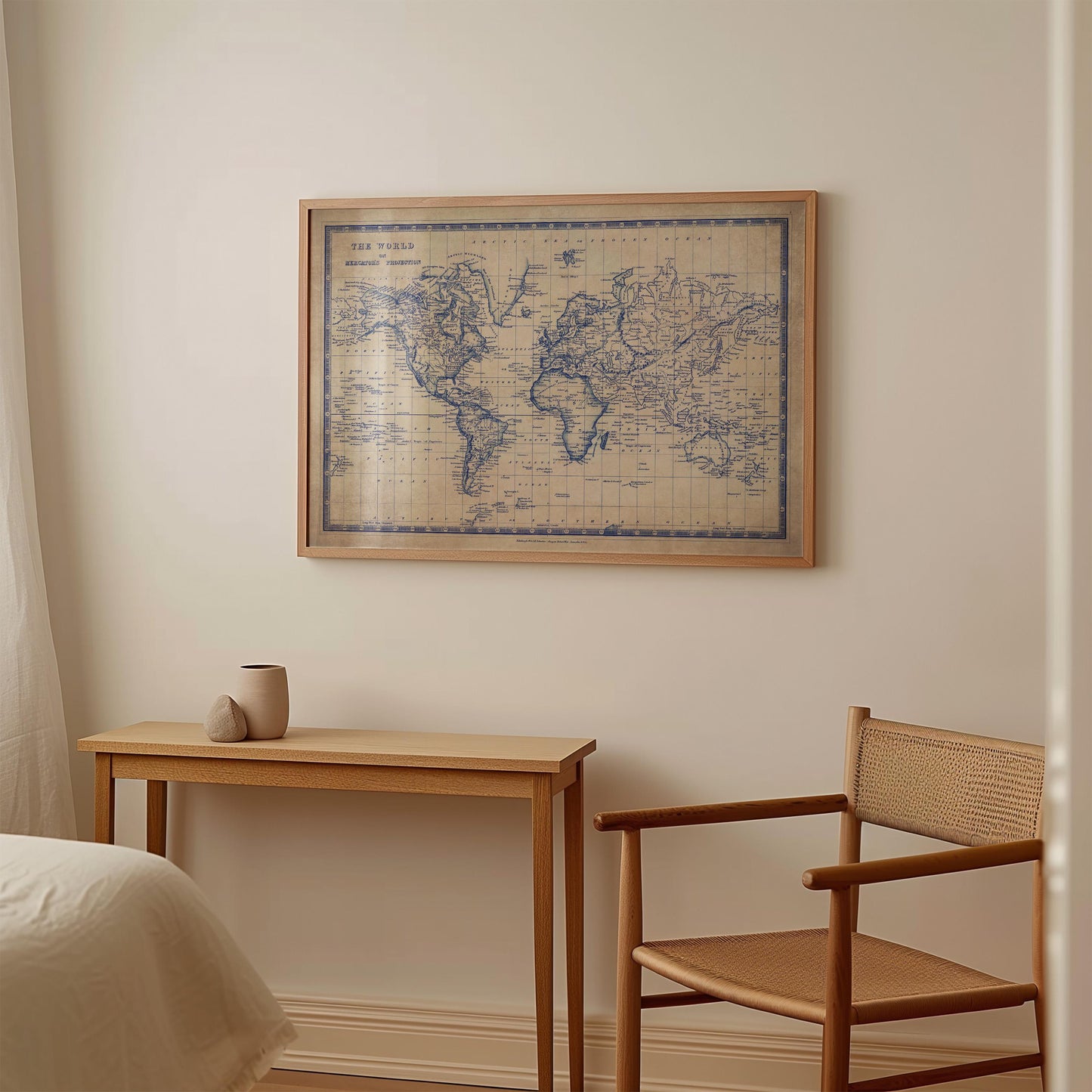 a wooden table with a cup on it, and a wooden chair next to it. Above the table, there is a framed world map hanging on the wall.