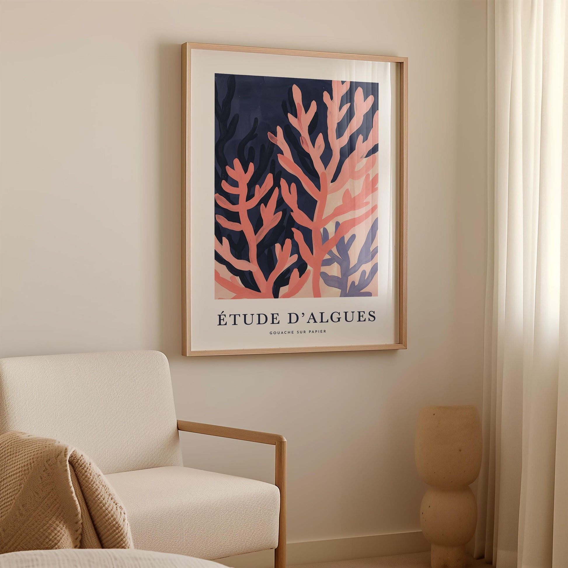 a framed artwork of coral on a wall, with a white sofa and a beige vase in the foreground.