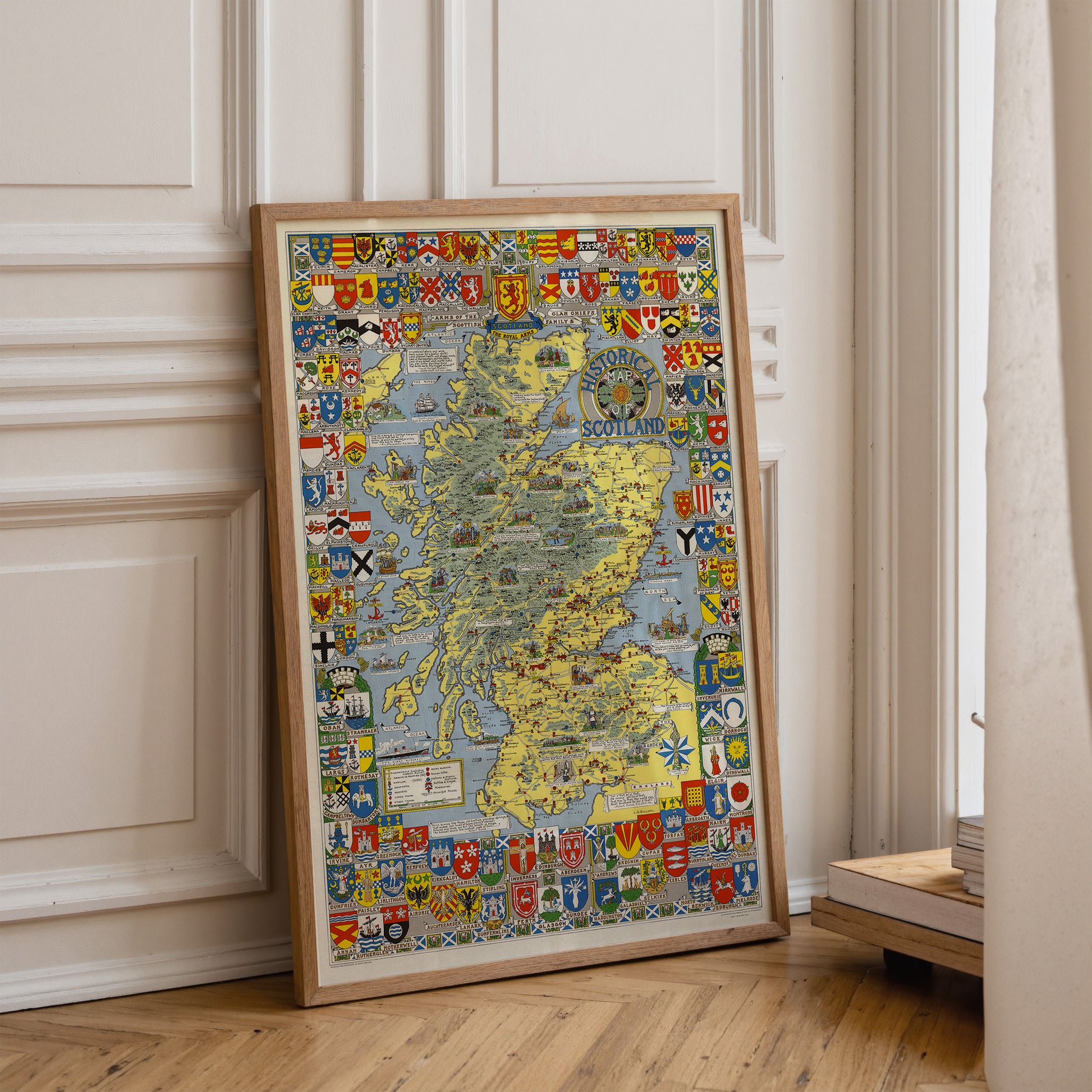 A framed map of Scotland is leaning against a white wall in a room.
