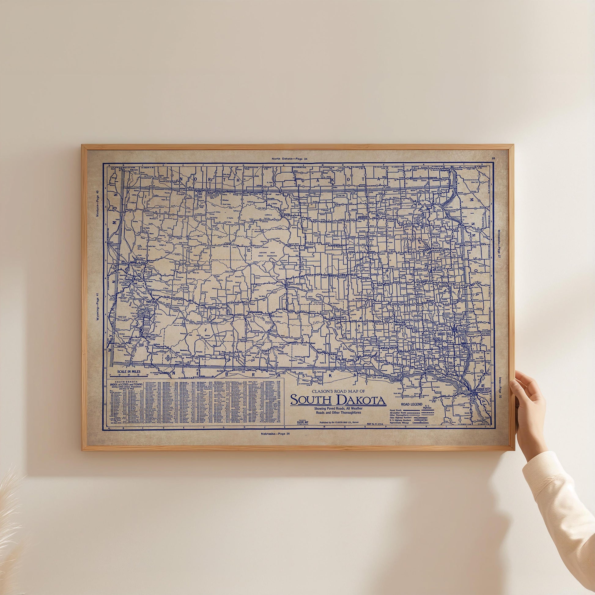 A person is holding up a framed map of South Dakota, which appears to be a vintage or historical map.