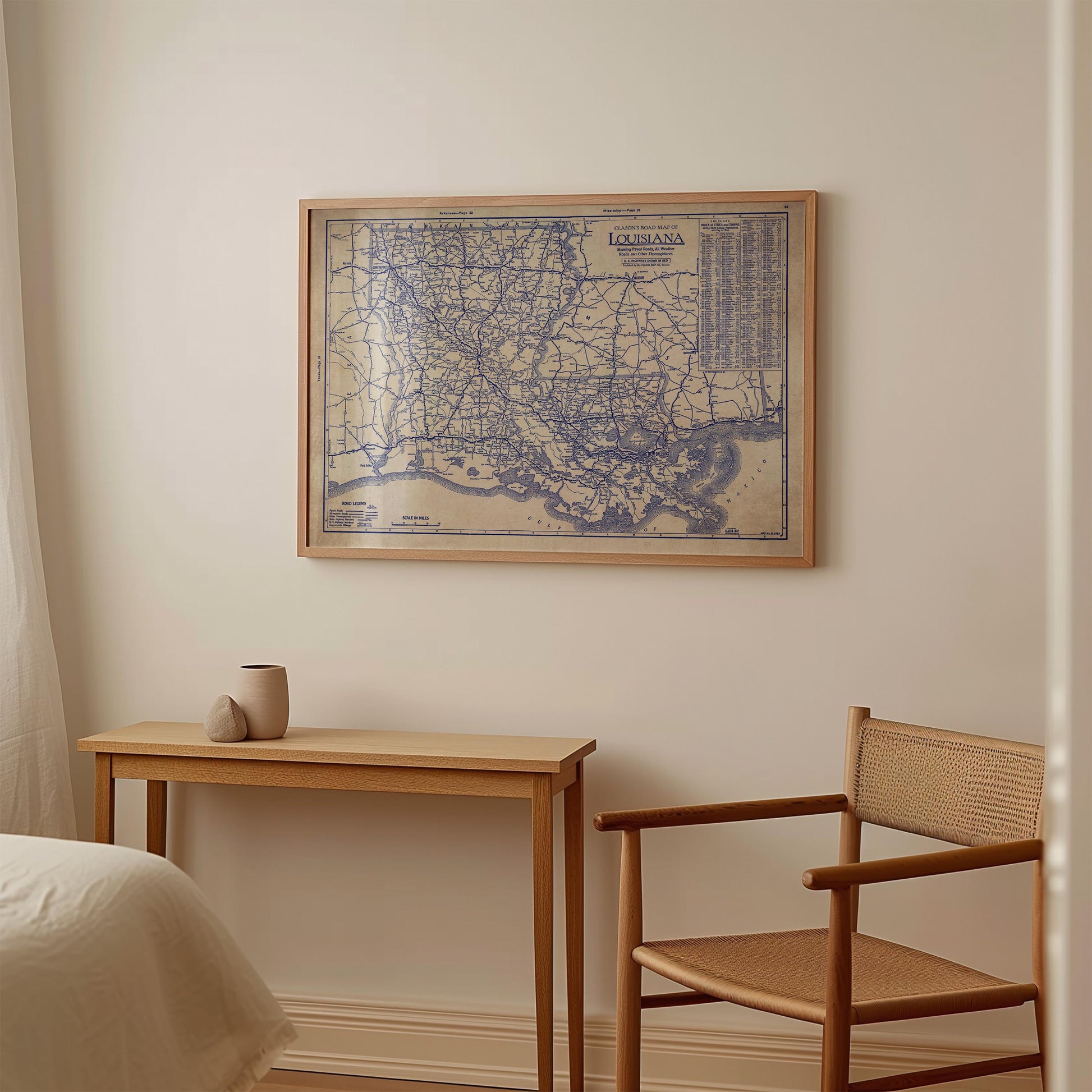 a framed map of Louisiana hanging on a wall, with a small table and a chair positioned below it.