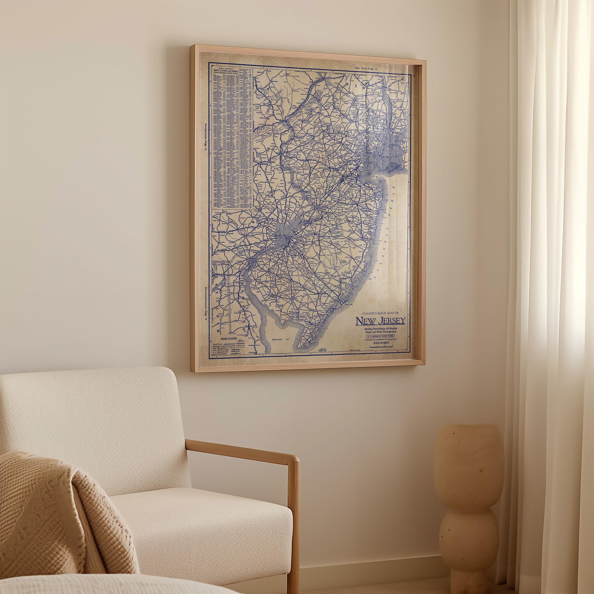 a framed map of New Jersey hanging on a wall in a room with a white sofa and a small sculpture.
