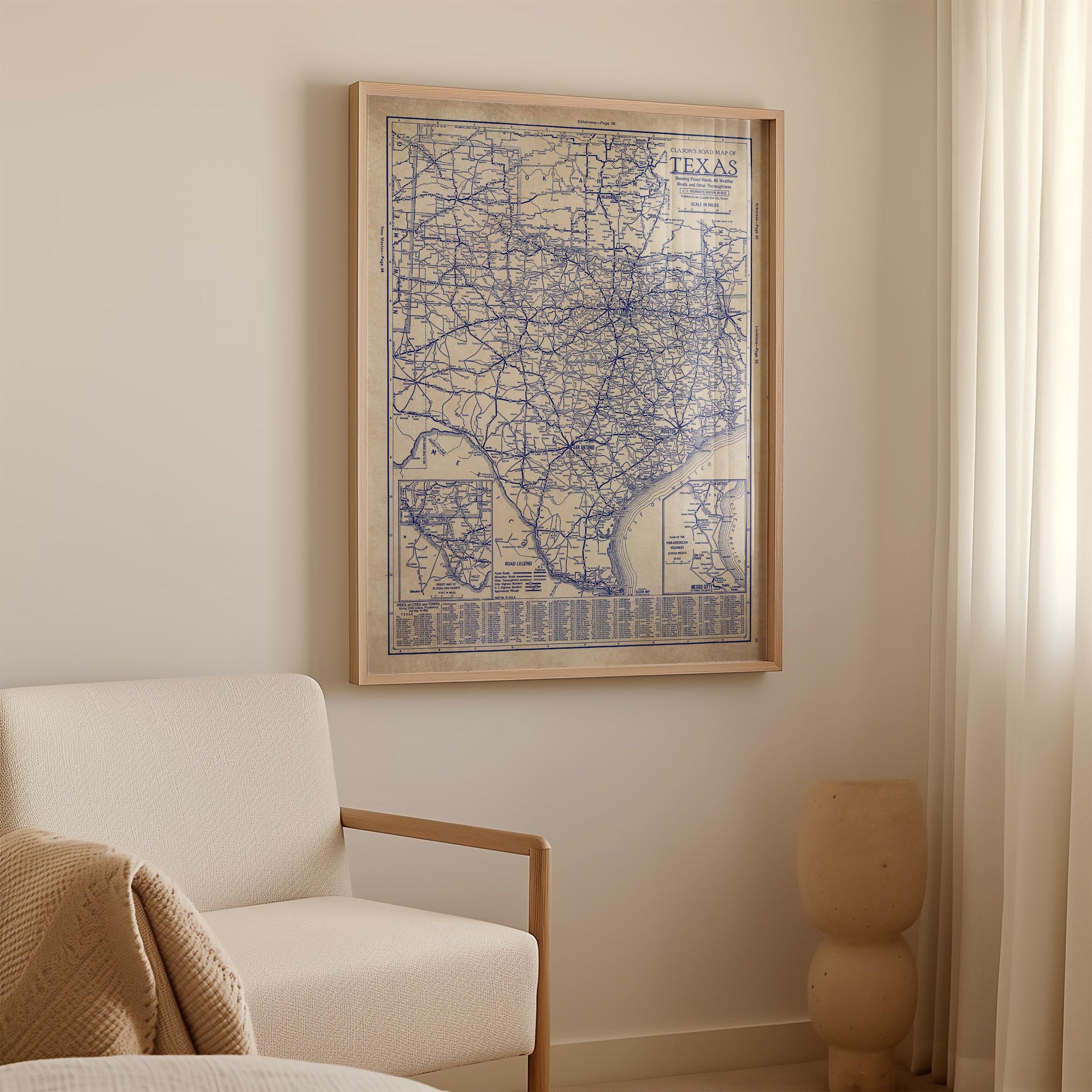 a framed map of Texas hanging on a wall in a room with a white sofa and a small sculpture.