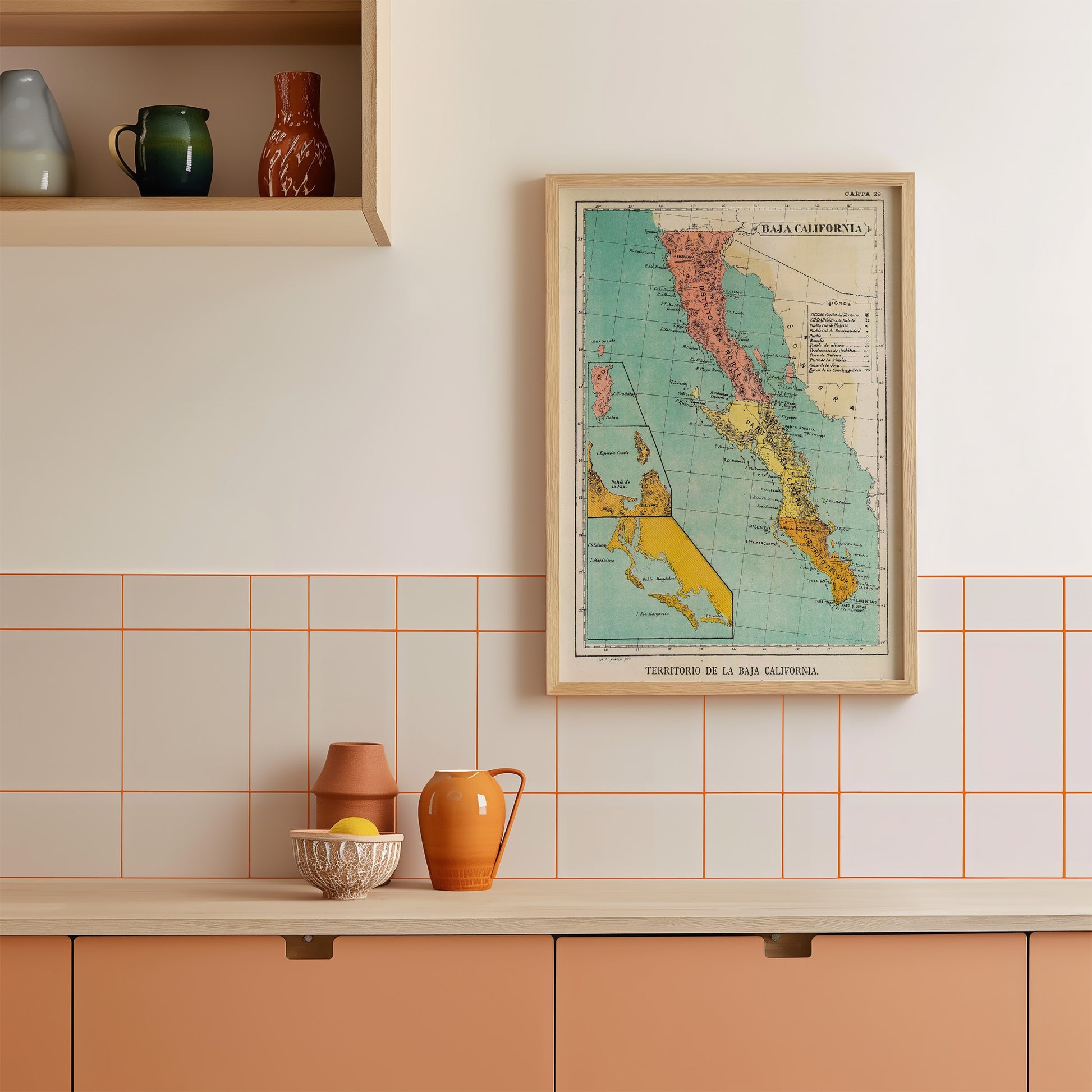 a kitchen counter with various items on it, including a framed map of California, a bowl, a pitcher, and a vase.