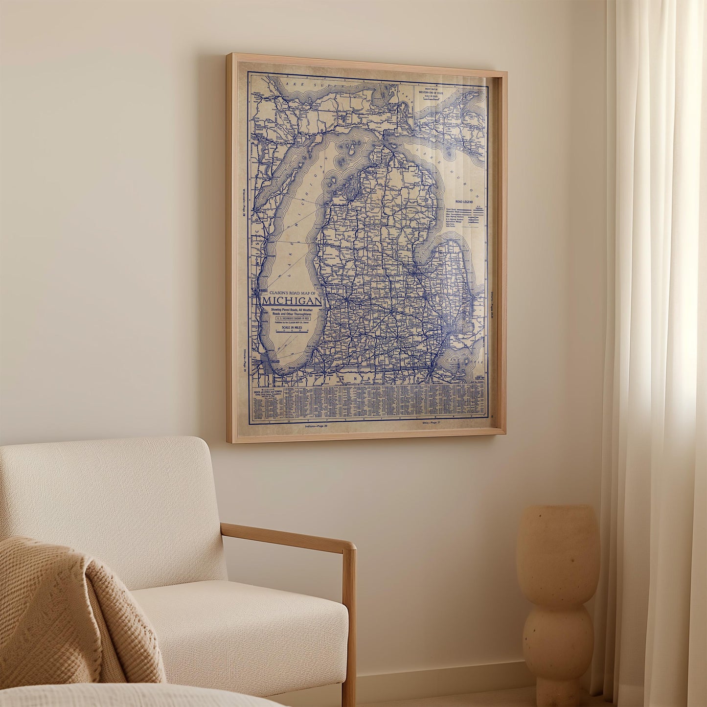 a framed map of Michigan hanging on a wall in a room with a white sofa and a small sculpture.
