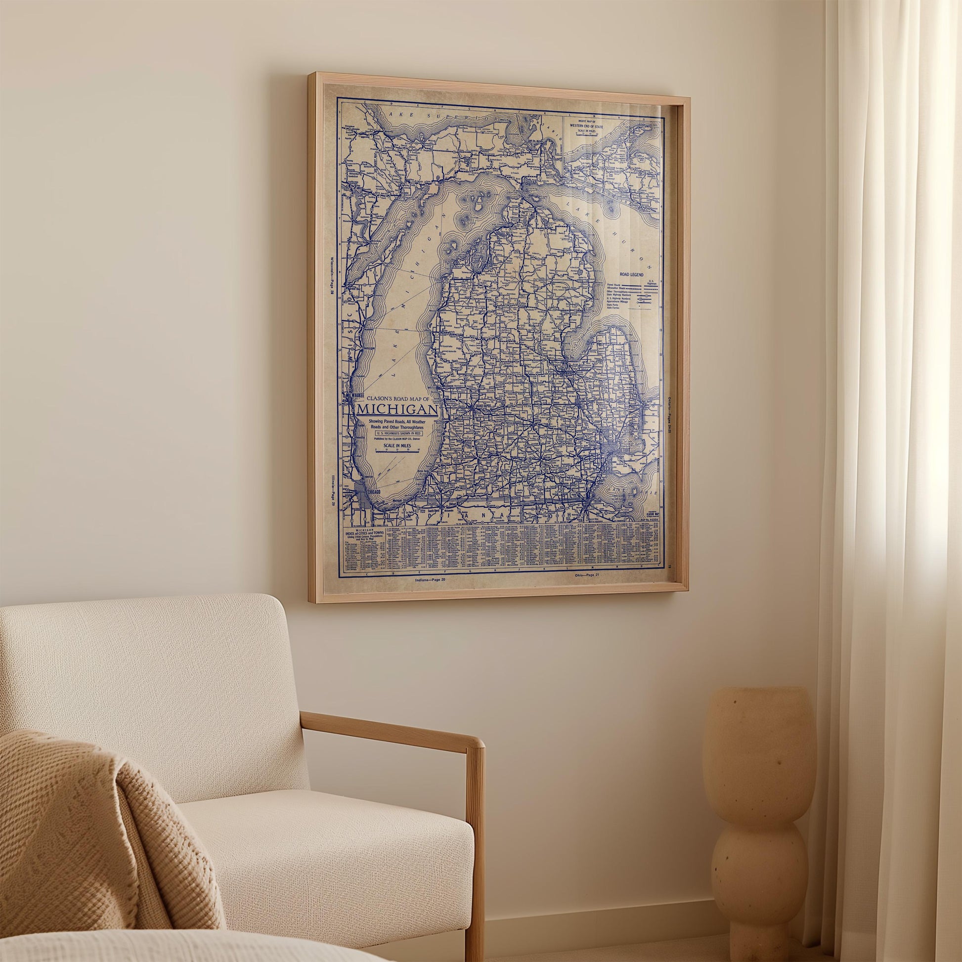 a framed map of Michigan hanging on a wall in a room with a white sofa and a small sculpture.