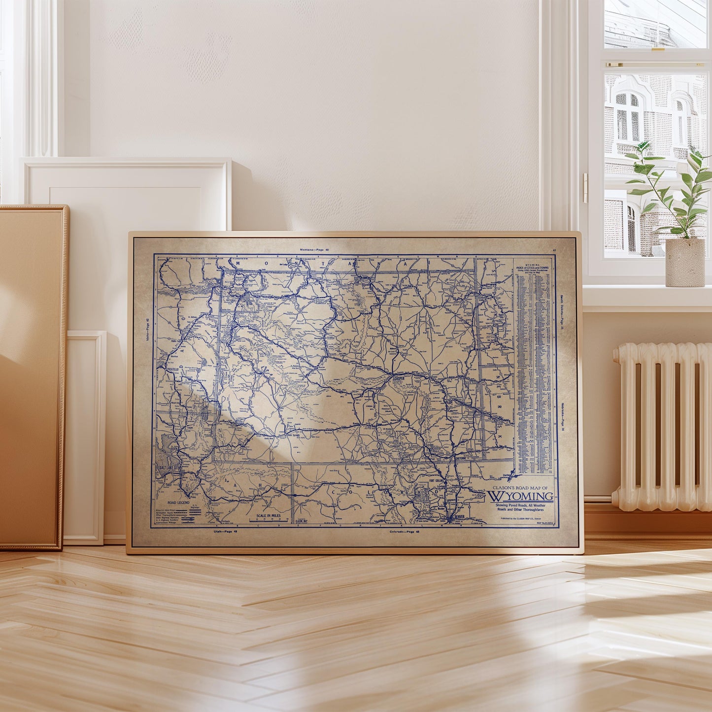 a framed map of Wyoming, with a wooden floor and a window in the background.