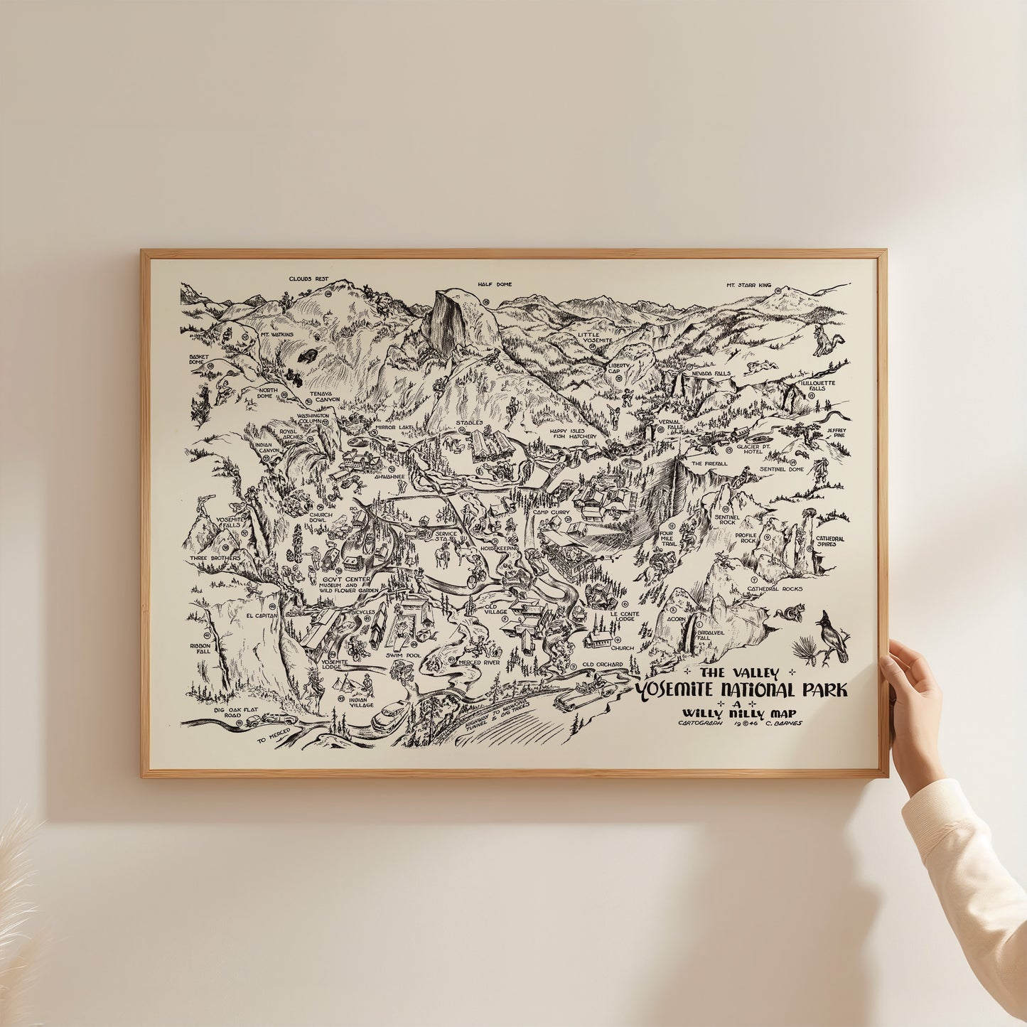 A person is holding up a framed map of Yosemite National Park, which is a black and white illustration depicting various landmarks and features of the park.