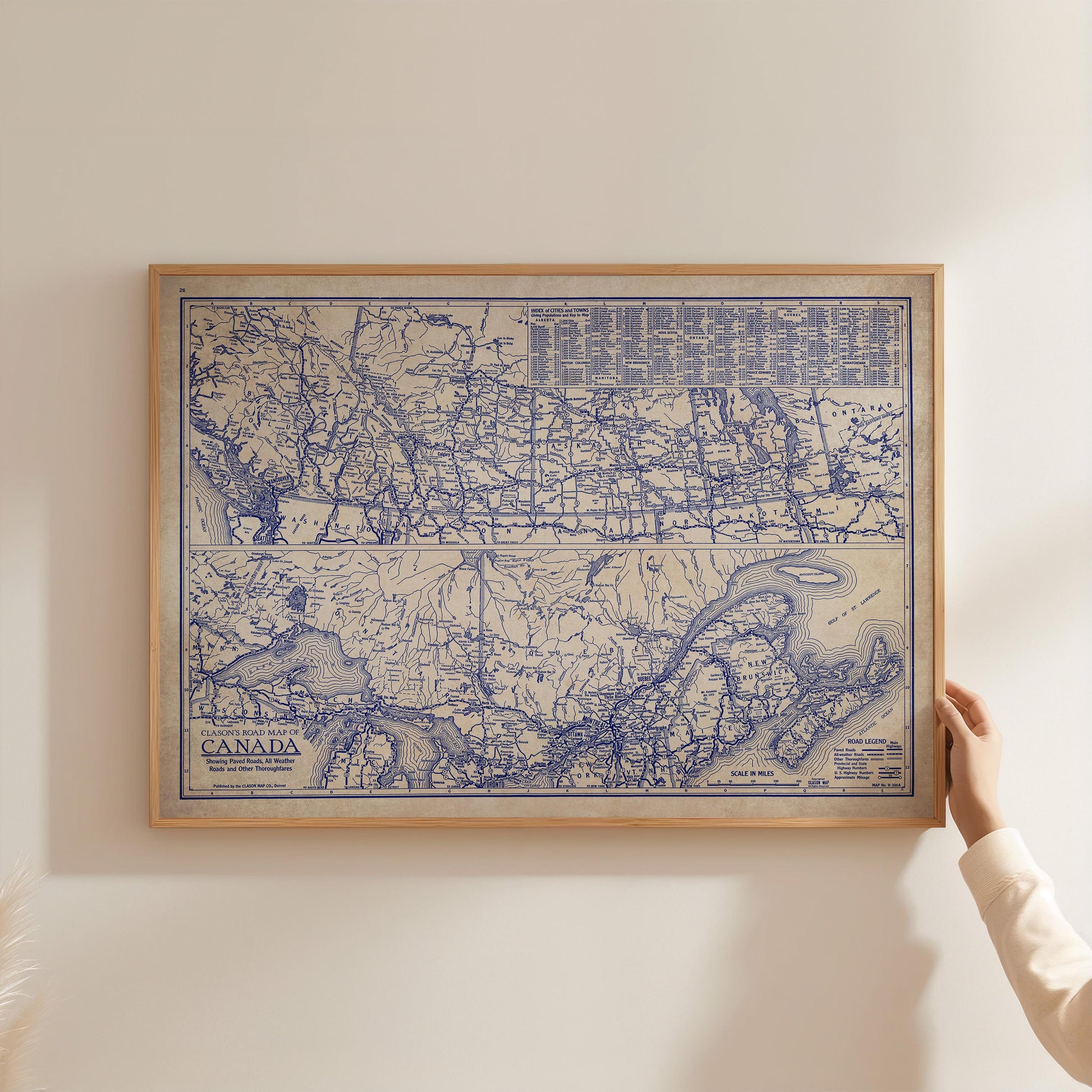A framed map of Canada is being held up against a white wall.