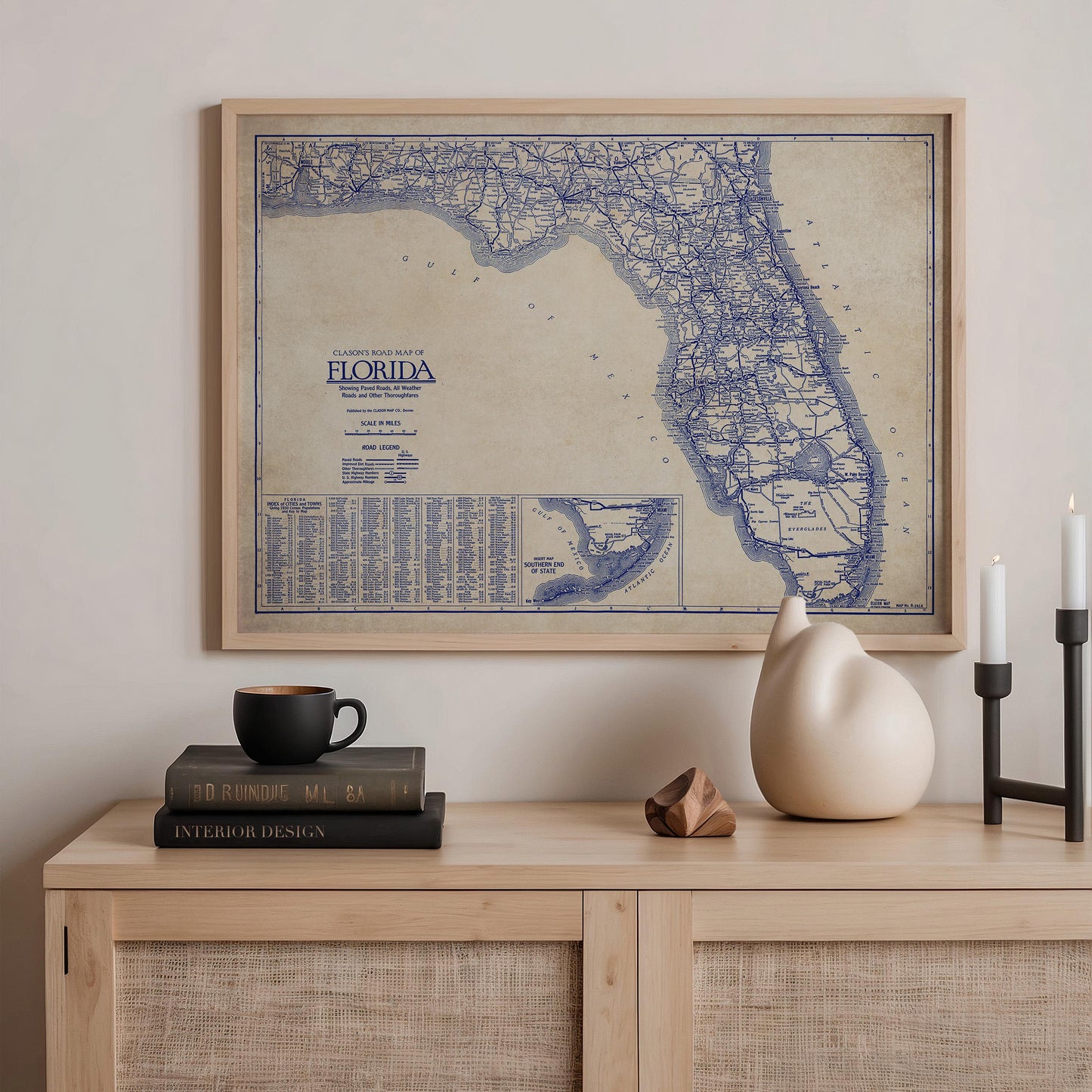 a framed map of Florida, a stack of books, a ceramic cat figurine, and a stack of books on a wooden shelf.