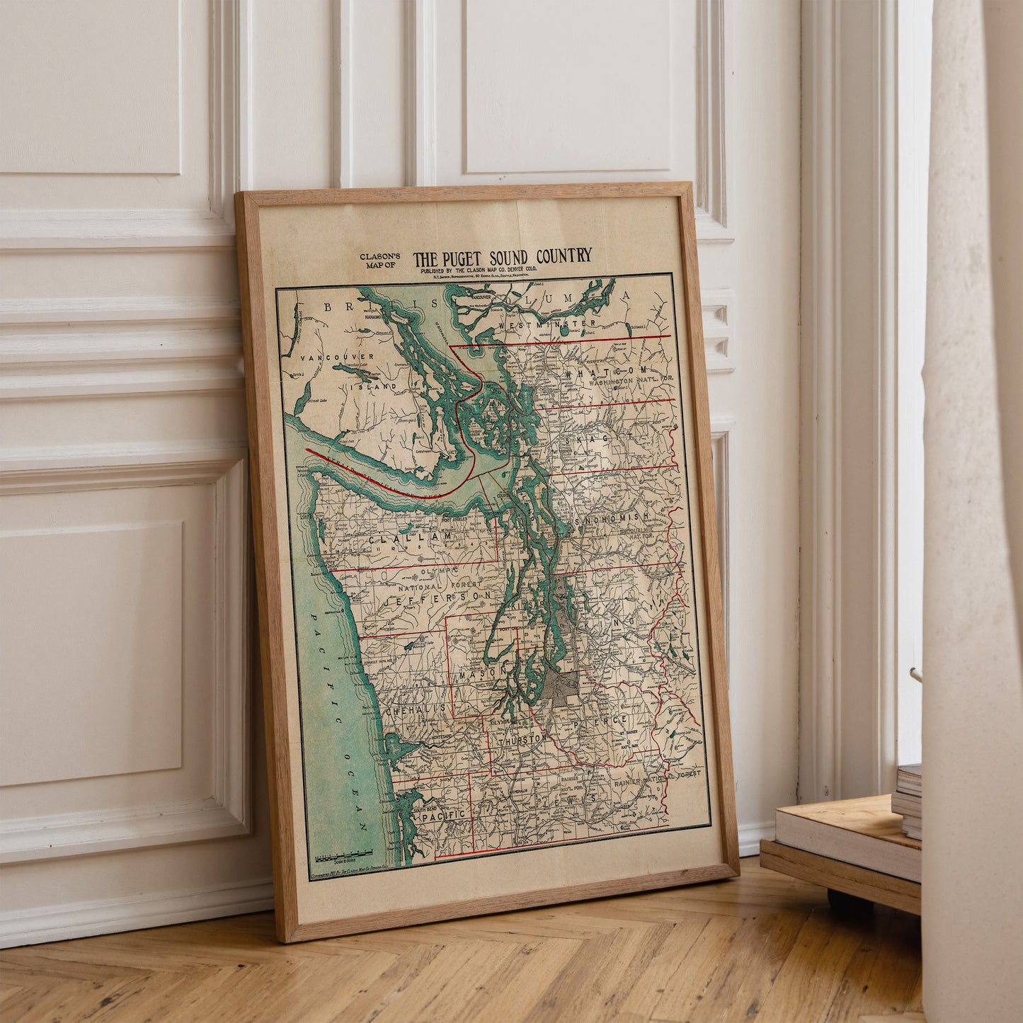 A framed map of the Puget Sound Country is leaning against a white wall.