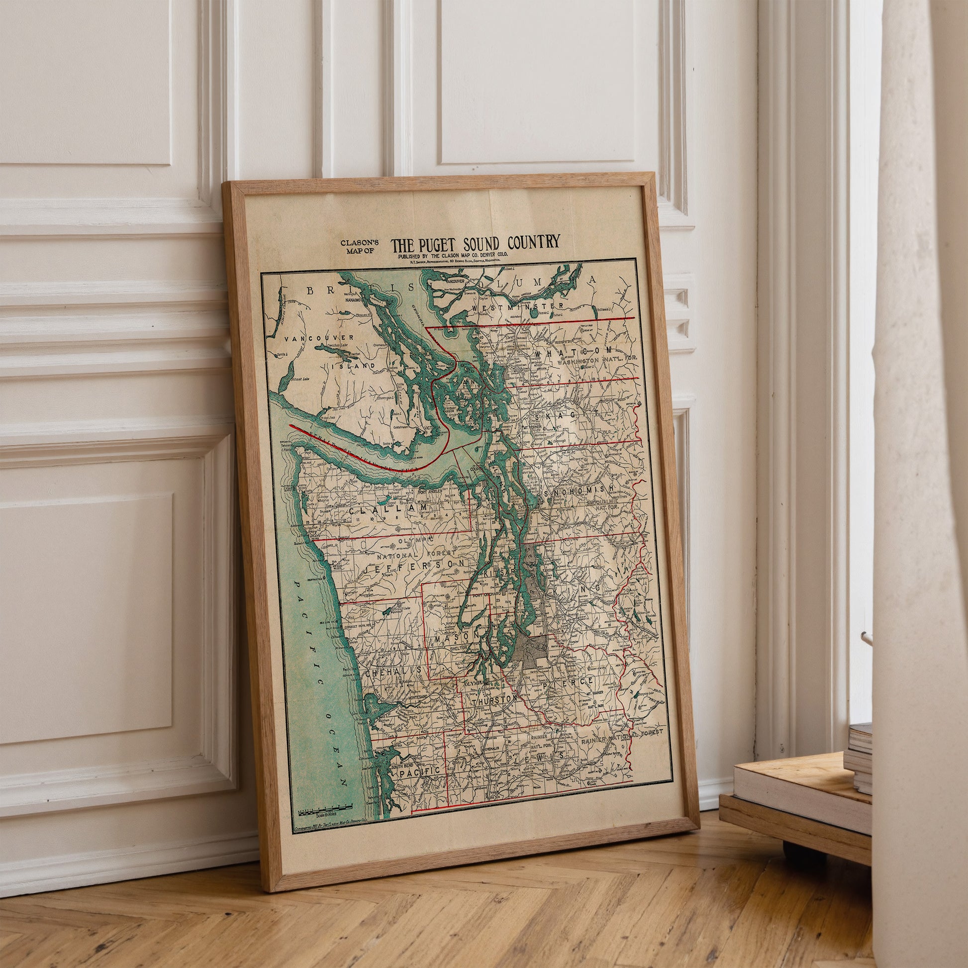 A framed map of the Puget Sound Country is leaning against a white wall.