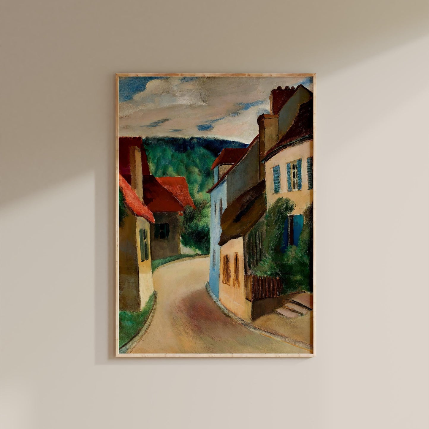 The image is a framed painting depicting a picturesque street scene with colorful buildings, trees, and a winding road.