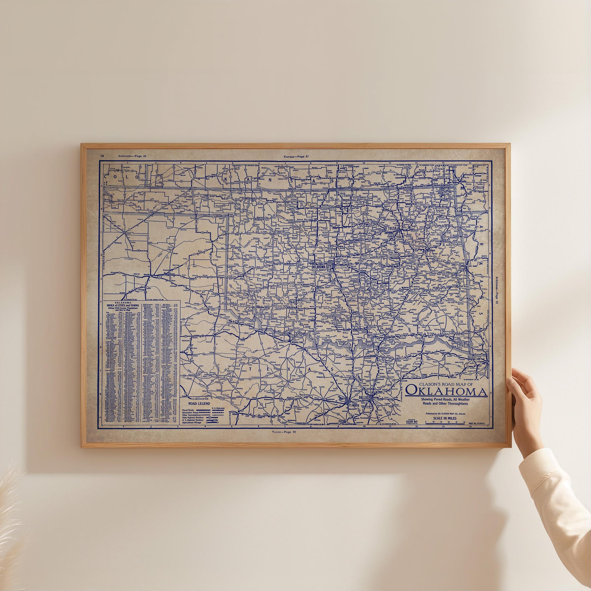 A person is holding up a framed map of Oklahoma, which appears to be a detailed and intricate map of the state.