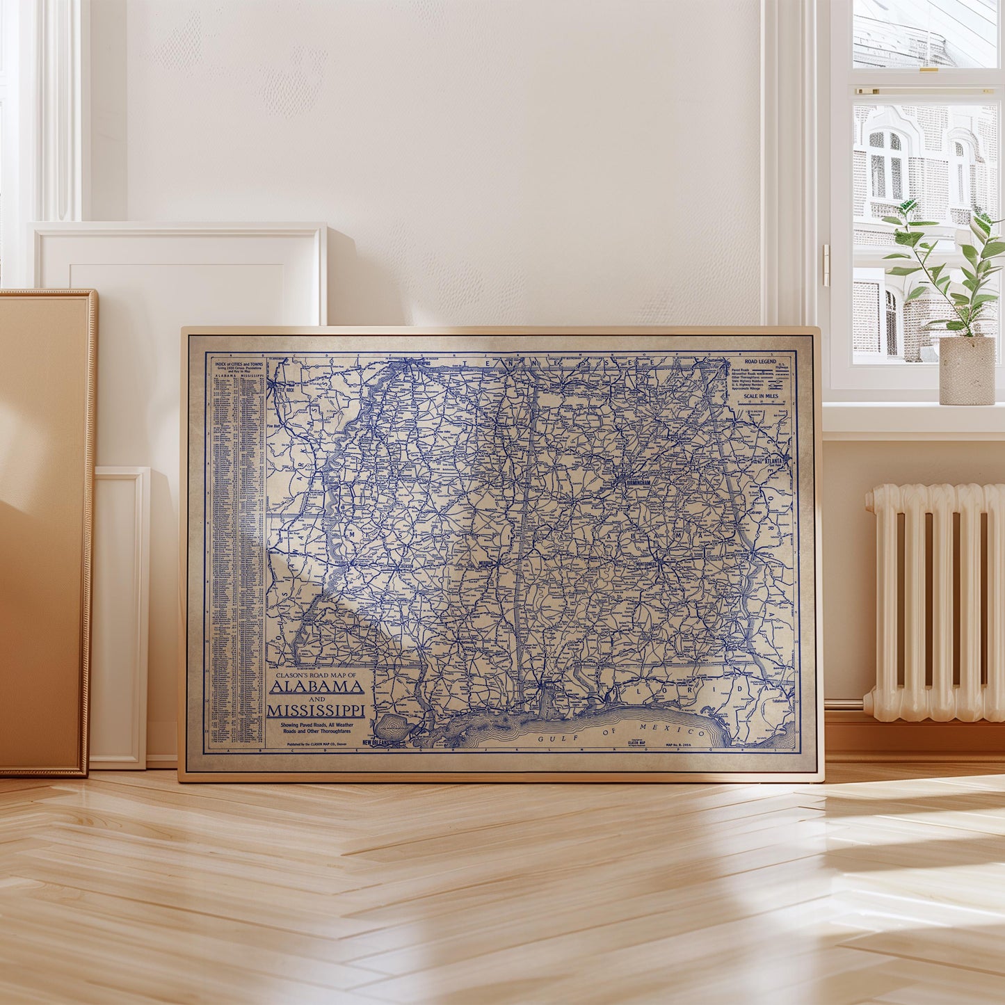 a framed map of Alabama, with a wooden floor and a window in the background.