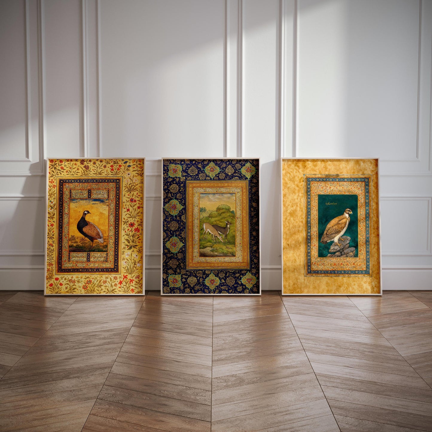 Three framed artworks of different styles and colors are displayed on a wooden floor against a white wall.