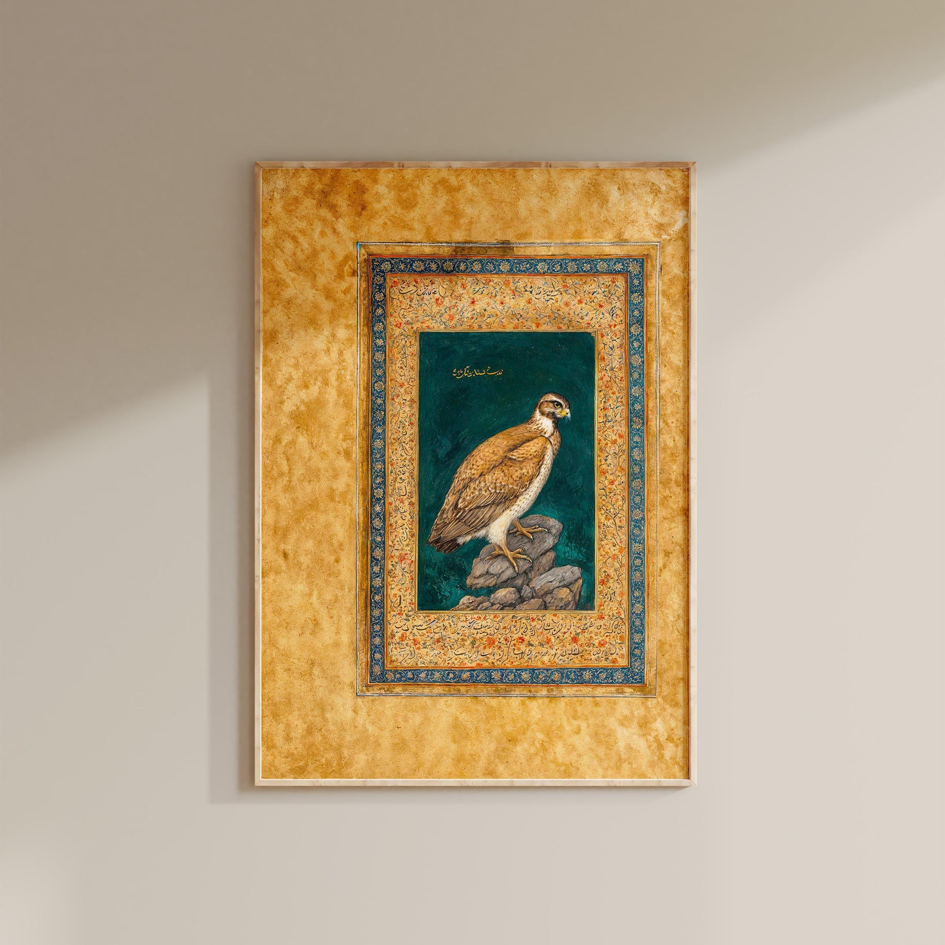 a framed painting of a bird, likely a hawk or falcon, perched on a rock.