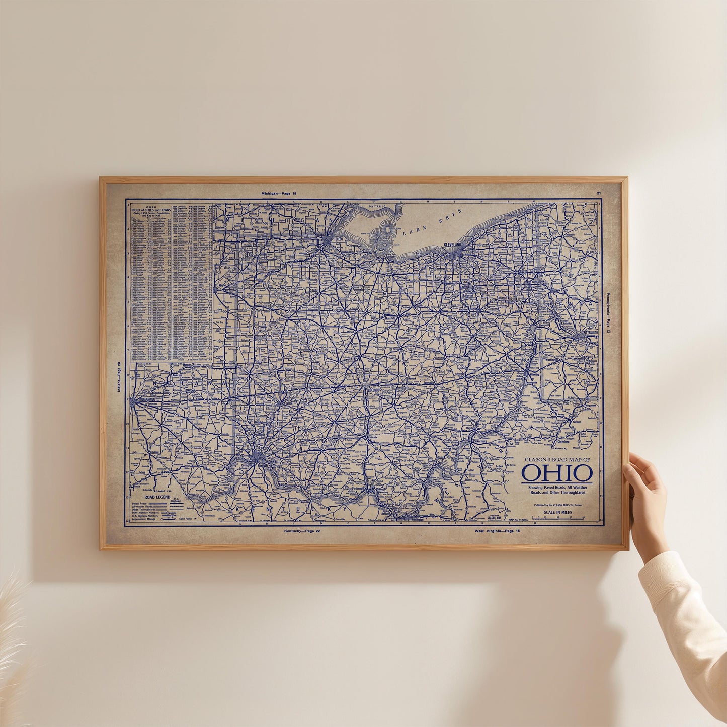 A person is holding up a framed map of Ohio, which appears to be a vintage or antique map.